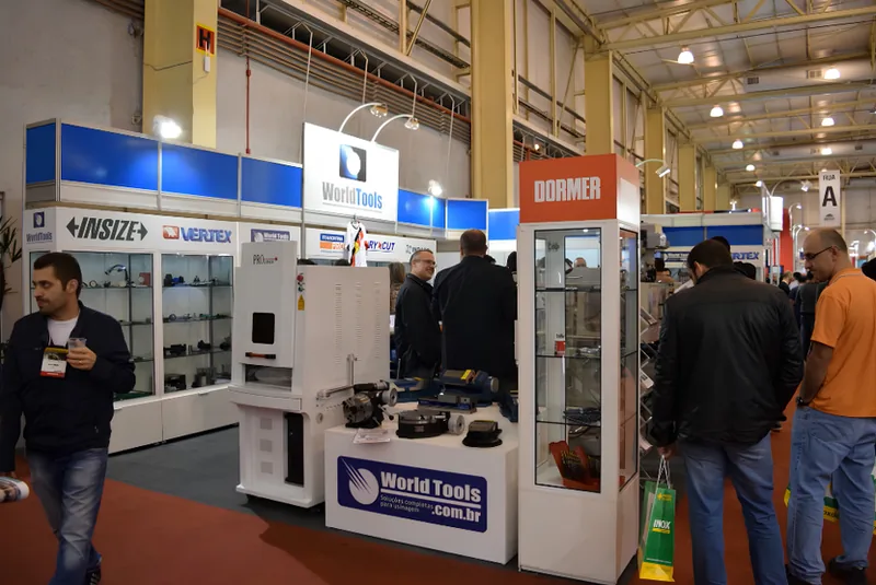 Estande de esquina da World Tools na Intermach 2015, com vitrines de produtos e visitantes circulando