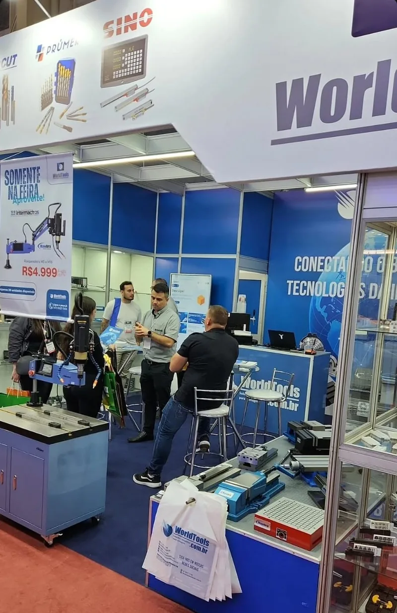 Dois integrantes da equipe World Tools em frente ao estande na Intermach 2025, com o banner de oferta exclusiva ao lado